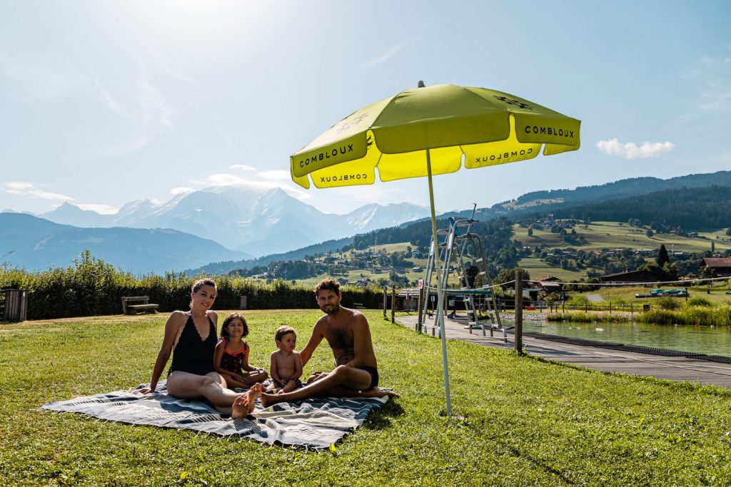 Family under a parasol in the lawn of the biotope body of water