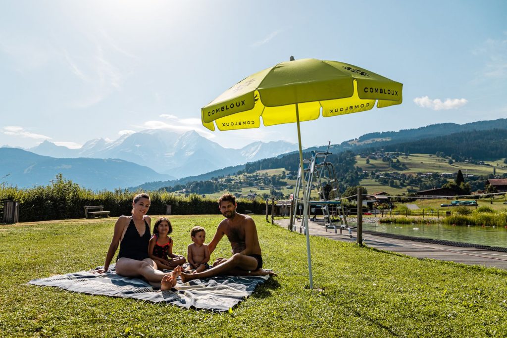 Famille sous un parasol dans la pelouse du plan d'eau biotope