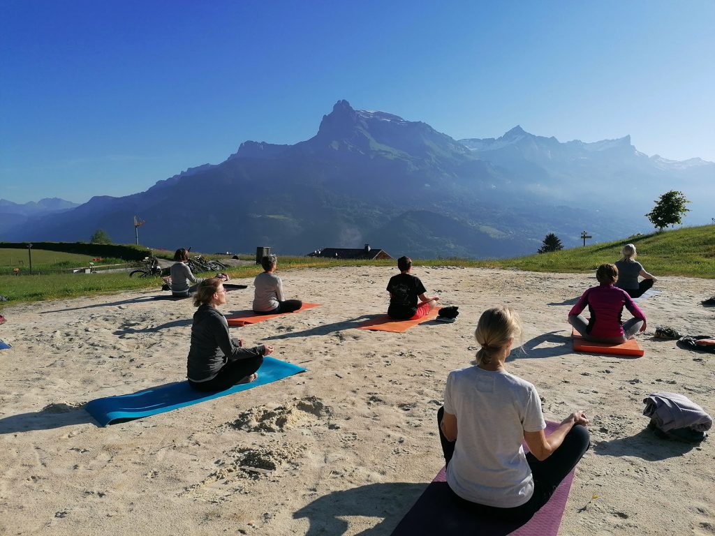 Yoguis al aire libre frente al fiz durante cumbres de bienestar.