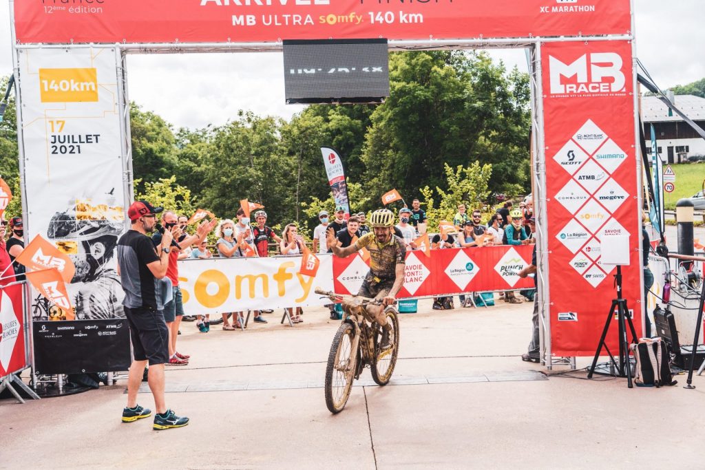 ciclista de montaña cruzando la línea de meta carrera mb en combloux