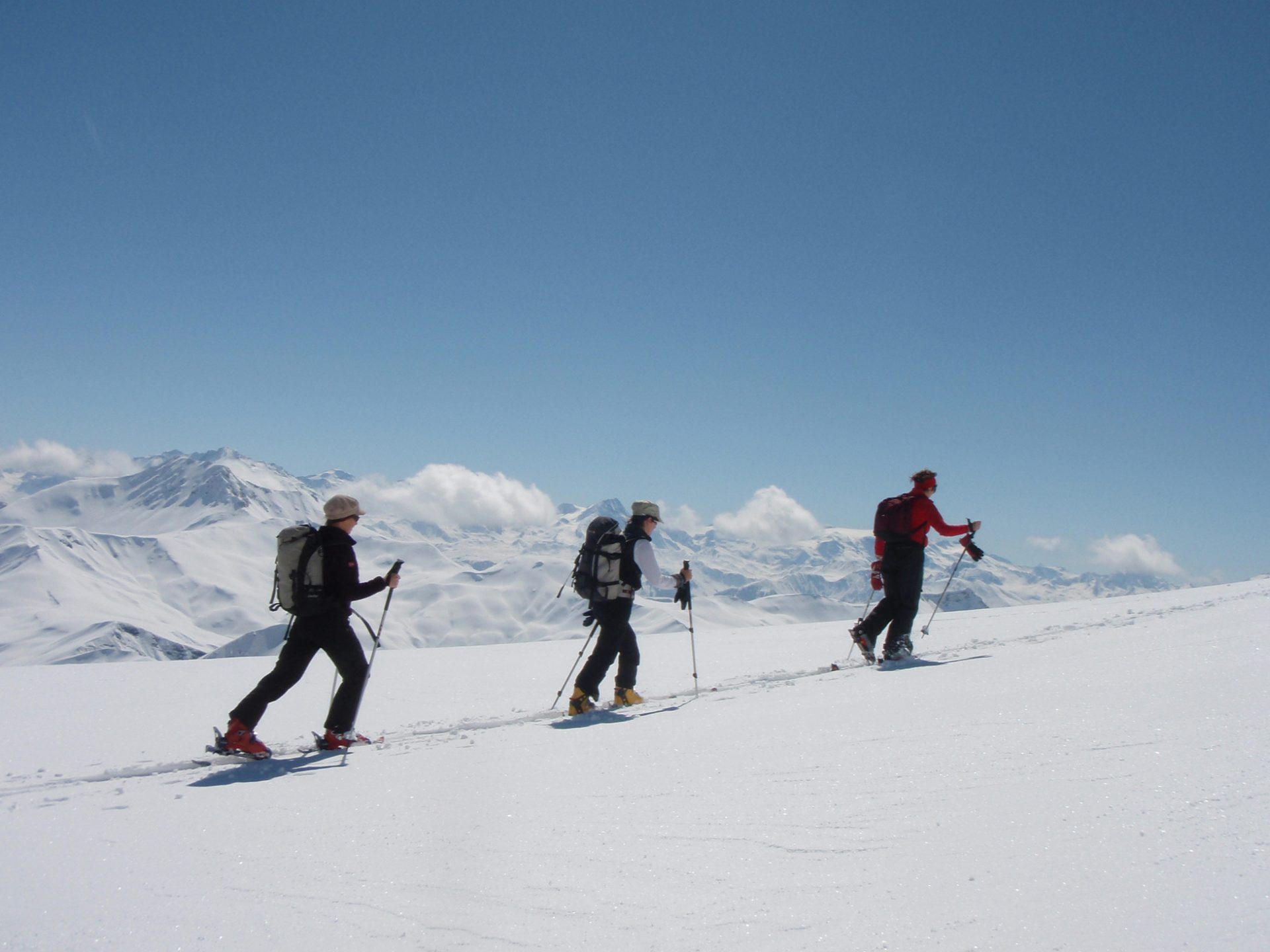 3 single file snowshoers in snowy mountainous landscapes