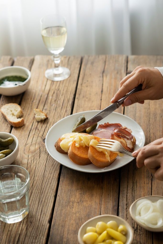 close-up raclette plate: melted cheese charcuterie potatoes