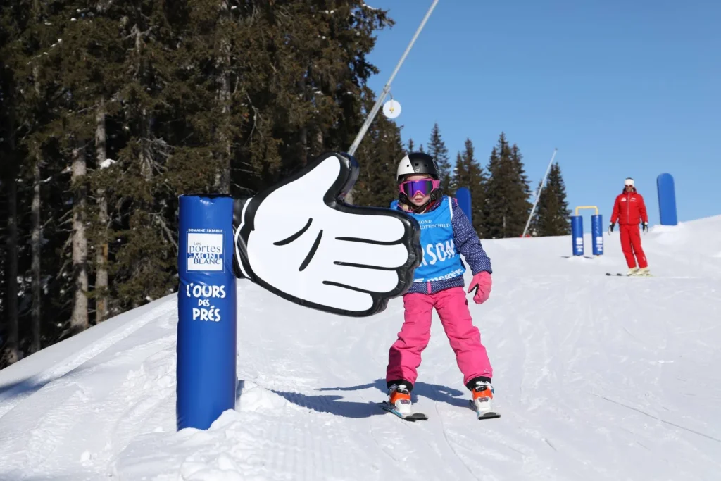 enfant en ski tapant main module zone ludique station combloux moniteur esf arriere plan