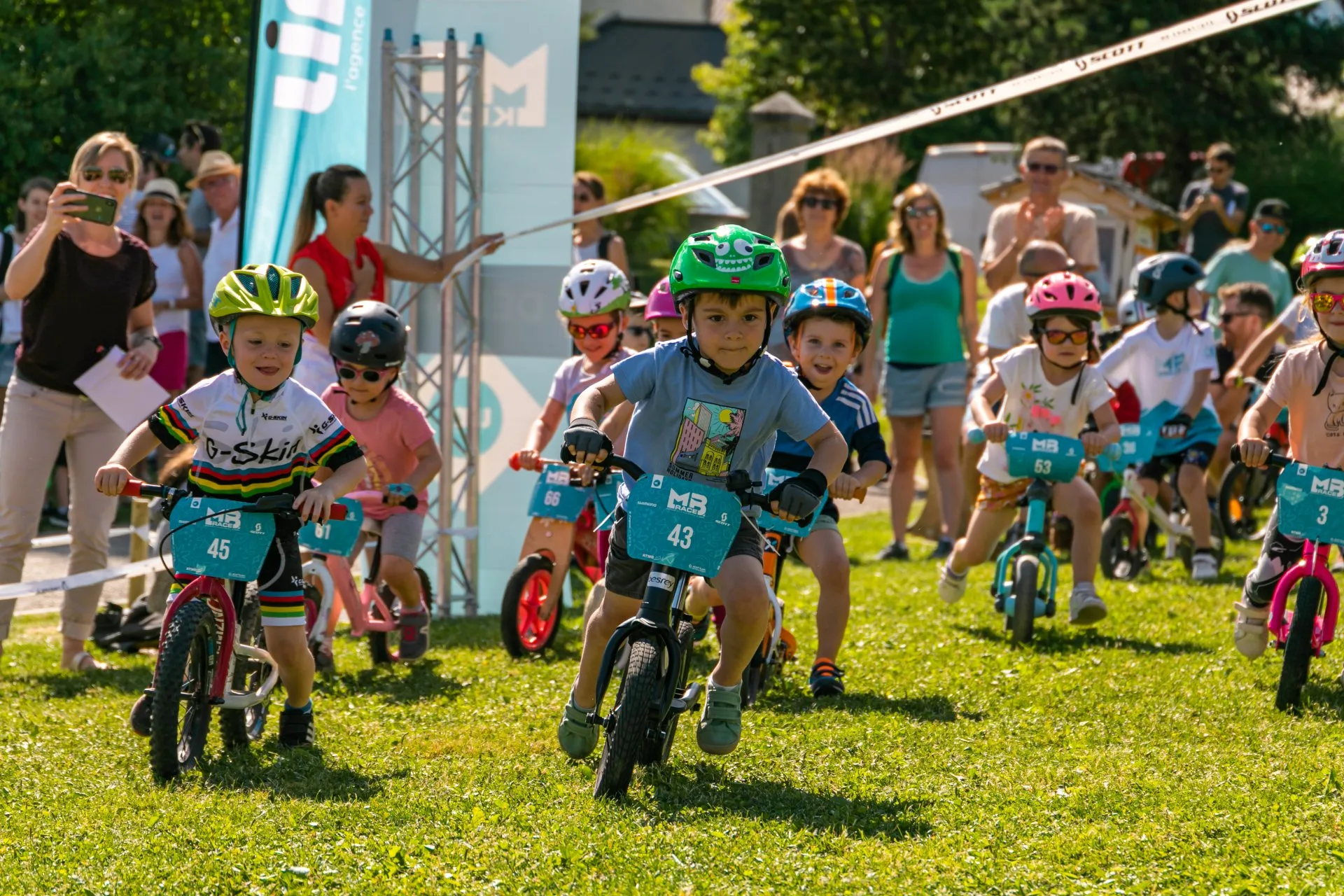 jeunes enfants en pleine course de VTT sur champ parents supporters