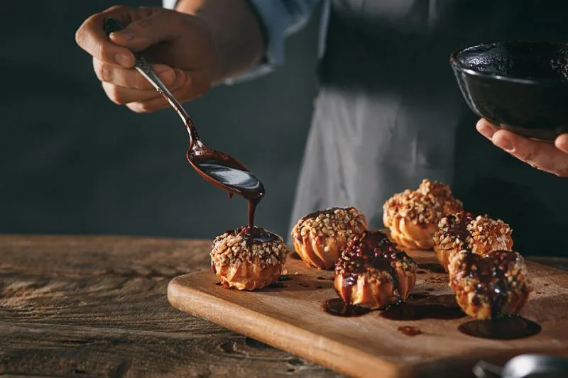 gros plan décorer de délicieux éclairs faits maison avec du chocolat et des arachides