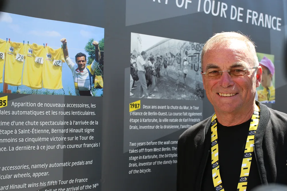 portrait actuel bernard hinaud devant image archives de lui maillot jaune