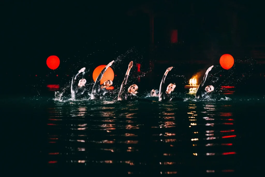 spectacle aquatique vivant combloux danse synchronisee dans eau ambiance sombre