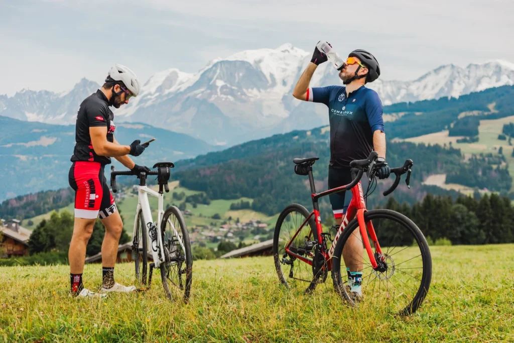 Dos hombres con bicicletas de carretera en los campos en el balcón frente al Mont Blanc