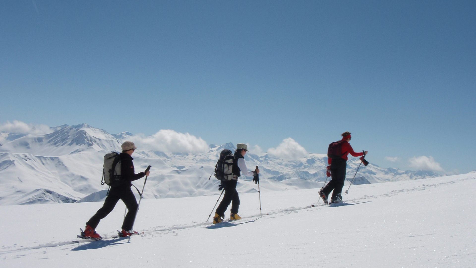 3 single file snowshoers in snowy mountainous landscapes