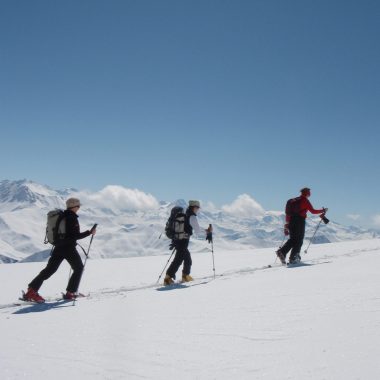 3 single file snowshoers in snowy mountainous landscapes