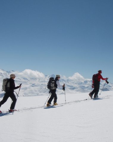 3 single file snowshoers in snowy mountainous landscapes