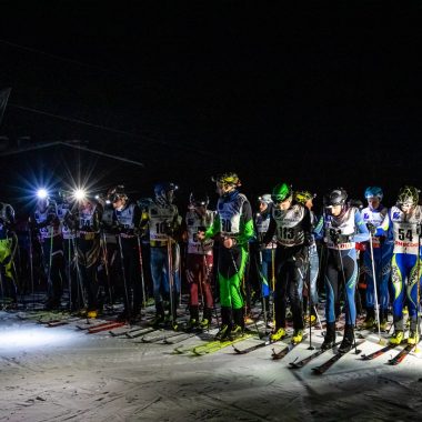 línea de salida desgarradora: esquiadores alineados por la noche, iluminación de faros