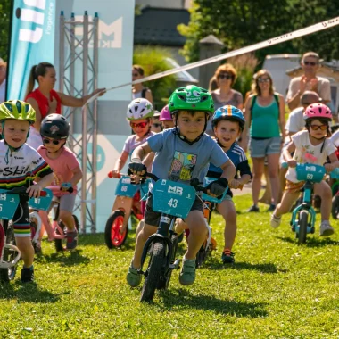 jeunes enfants en pleine course de VTT sur champ parents supporters