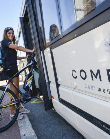 Una joven subiendo al autobús de la estación Combloux con su bicicleta