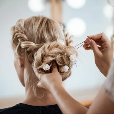 blonde woman from behind having her hair done for wedding combloux