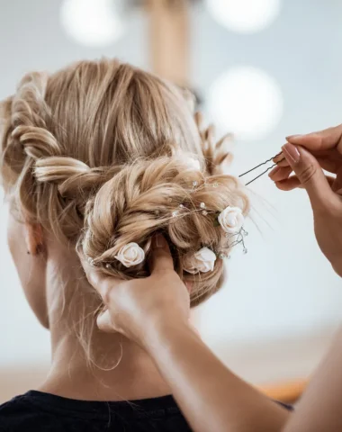 blonde woman from behind having her hair done for wedding combloux