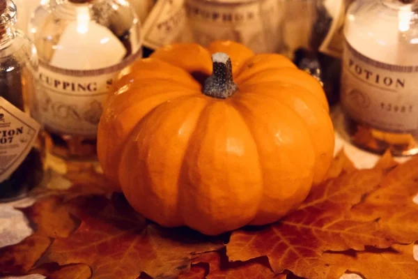 halloween pumpkin surrounded by candles on bed of dead leaves