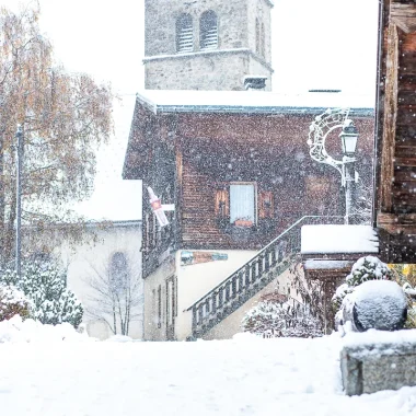 snowfall in progress in front of bakery and church