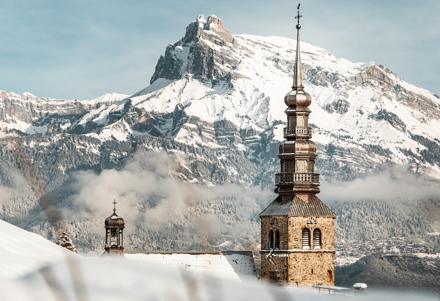 Bell tower of the Church of Combloux in a snowy landscape