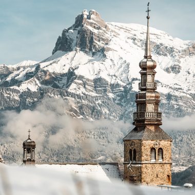 Bell tower of the Church of Combloux in a snowy landscape